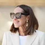 Stilvolle Frau mit mittellangem Haar, Sonnenbrille und auffälligem Ohrring. Perfekt für unkomplizierte Frisuren mittellang ab 50.