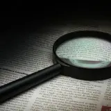 Lupa powiększa tekst, symbolizując dociekliwość i spostrzegawczość – kluczowe cechy dobrego detektywa.