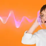 Chłopiec z otwartymi ustami przykłada dłoń do ucha, jakby nie słyszał poleceń. Fale dźwiękowe unoszą się obok.