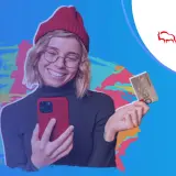 Uśmiechnięta młoda kobieta z telefonem i kartą Banku Pekao. Jej konto przekorzystne pekao to klucz do finansowej swobody.