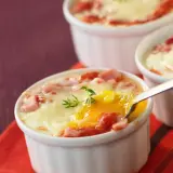 Œufs cocotte au four, jambon et fromage fondus, un délice crémeux prêt à être dégusté.