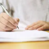 Dłoń pisze długopisem na dokumencie. Umowa najmu na czas określony przechodzi na czas nieokreślony.