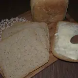 Chleb pszenno żytni na zakwasie, pokrojony w kromki. Jedna kromka posmarowana masłem, obok leżą kolejne.