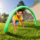 A boy crawls through a green pool noodle arch at a fun elementary school fall festival. Great ideas for outdoor games!