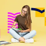 Dziewczyna pisze w zeszycie, przygotowując się do matury z angielskiego. Szuka inspiracji i przykładów wypowiedzi pisemnych.
