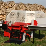 Roter Holzspalter mit 20T-Aufschrift, bereit für das nächste Holzspalter-Angebot. Im Hintergrund ein großer Stapel gespaltenes Holz.