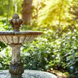 Ein antiker Gartenbrunnen sprudelt im Sonnenlicht. Tolle Ideen für Brunnen im Garten, die Ruhe und Schönheit bringen.