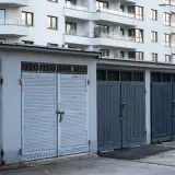Rząd garaży wolnostojących zamykanych na kłódki, na tle nowoczesnego bloku mieszkalnego. Zastanawiasz się, ile kosztuje garaż wolnostojący?