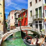 Gondolier w tradycyjnym stroju, gotów do rejsu. Słychać pieśń gondolierów weneckich, gdy przepływa pod mostem.