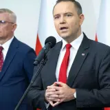 Mężczyzna w garniturze mówi do mikrofonu, obok stoi drugi mężczyzna. Dyskutują, dlaczego prezydent chce zwiększenia budżetu na Biuro Bezpieczeństwa Narodowego o 15 procent.