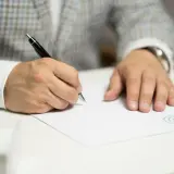Main tenant signe un document, une action qui ne sera jamais déposée.