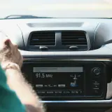 Ręce na kierownicy, radio samochodowe pokazuje 91.5 MHz. Wygodne środki masowego przekazu w podróży.