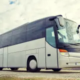 Biały autokar turystyczny na tle nieba z chmurami.