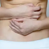 Mani che stringono l'addome per alleviare le coliche addominali. Rimedi naturali per il mal di pancia.
