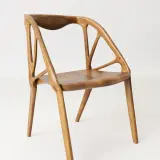 A modern wooden chair with an intricate, skeletal backrest. The chair building showcases organic curves and a light, airy design.
