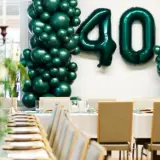 Elegancka impreza urodzinowa dla dorosłych z balonami tworzącymi liczbę 40. Uroczysty stół z zastawą i świecami.