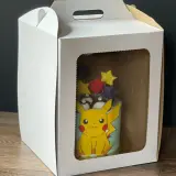 Tort z Pikachu w białym pudełku z okienkiem.