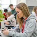 Młoda technik ochrony środowiska bada próbki pod mikroskopem w laboratorium.