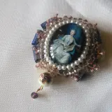 Broche con camafeos, perlas y detalles florales. Una dama elegante lee un libro en un retrato ovalado, rodeada de encaje y cristales.