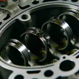 Nahaufnahme eines Motors mit sichtbaren Kolbenringen. Ablagerungen deuten auf defekte Kolbenringe Symptome hin.