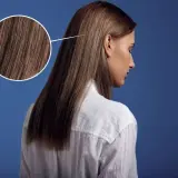 Primer plano de un cabello castaño sedoso, con un círculo que amplía los detalles. Parece que el pelo está en pausa, esperando un nuevo estilo.