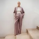 Elegancki różowy garnitur w prążki to idealna propozycja, jak się ubrać na poprawiny. Długie, szerokie spodnie i marynarka tworzą stylowy look.