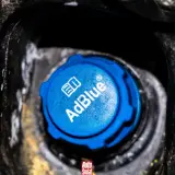 Niebieski korek wlewu AdBlue w samochodzie, z widocznym logo i napisem.
