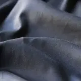 Plis du polyester tissu, d'une teinte gris foncé, créant des ombres douces et des reflets subtils.