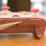 Chwytak naciska przycisk parowania na różowym padzie Xbox, pokazując, jak sparować pada Xbox.