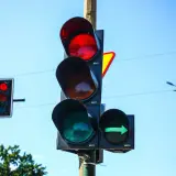 Sygnalizator S2 z zieloną strzałką w prawo i czerwonym światłem na głównym słupku. Niebo błękitne.
