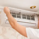 Technik sprawdza filtry klimatyzatora. Czy montaż klimatyzacji wymaga zgłoszenia? Zależy od przepisów.