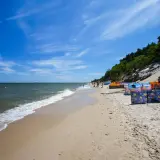 Słoneczna plaża w Chłapowie z kolorowymi parawanami, idealne miejsce na rodzinne wakacje i atrakcje dla dzieci.