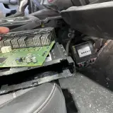 Naprawa modułu komfortu w Oplu, błąd dtc u0140. Widoczna zielona płytka drukowana z elementami elektronicznymi.