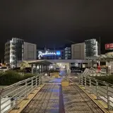 Nocny widok na hotel Radisson Blu Hamburg. Widać logo hotelu, znak Turkish Airlines i wejście.