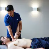 Ein Osteopath behandelt einen jungen Mann am Arm. Die Frage, wie oft Osteopathie hilft, wird hier visuell beantwortet.