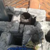 Szlamowanie komina: szczotka i rura wylotowa na dachu, gotowe do czyszczenia.