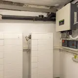 Dwa białe, modułowe systemy **bess** obok siebie, podłączone do falownika i rozdzielnicy elektrycznej.