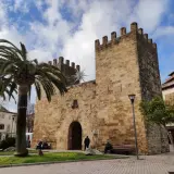 Puerta de Alcudia, Valencia, con palmeras y cielo azul.