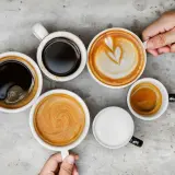 Różne rodzaje kawy, od espresso po latte, ułożone na szarym blacie. Czy kawa wypłukuje magnez? To pytanie nurtuje wielu miłośników tego napoju.