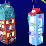 Zwei selbstgebastelte Laternen in Hausform, leuchten im Dunkeln. Kinder haben hier ihre Kreativität beim Laternen basteln gezeigt.