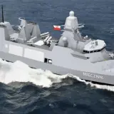 Nowoczesna fregata ORP Miecznik, część polskiej marynarki wojennej, z helikopterem na pokładzie, pruje fale.