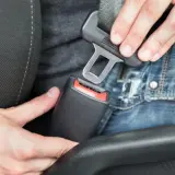 Persona abrochando el cinturón de seguridad en un coche. En un turismo es obligatorio utilizar los cinturones de seguridad.