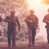 Czterech żołnierzy w kamuflażu, z karabinami, idzie przez las. Czy to przygotowanie do "Escape from Tarkov wymagania"?