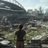 Widok na postapokaliptyczne miasto wewnątrz stadionu, gdzie ludzie żyją w prowizorycznych domach. Może to być scena z The Last of Us sezon 3.