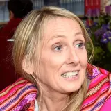Beata Pawlikowska z kolorowym szalem na tle książek i kwiatów.