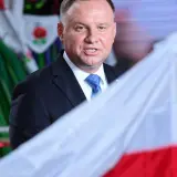Prezydent Andrzej Duda z polską flagą, w tle ludowy strój. Może to symbolizować ułaskawienie i dumę narodową.