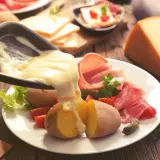 Raclette, le meilleur plat français, avec pommes de terre, charcuterie et fromage fondu. Un délice réconfortant.