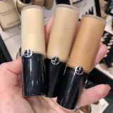 En hand håller tre flaskor Giorgio Armani foundation i olika nyanser.