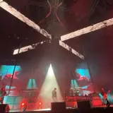 Deftones koncert Polska. Wokalista na scenie, gitarzyści grają, a za nimi ekrany z wizualizacjami.