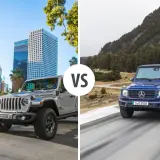Szary Jeep Rubicon na tle miasta kontra niebieski Mercedes G-klasa na górskiej drodze.